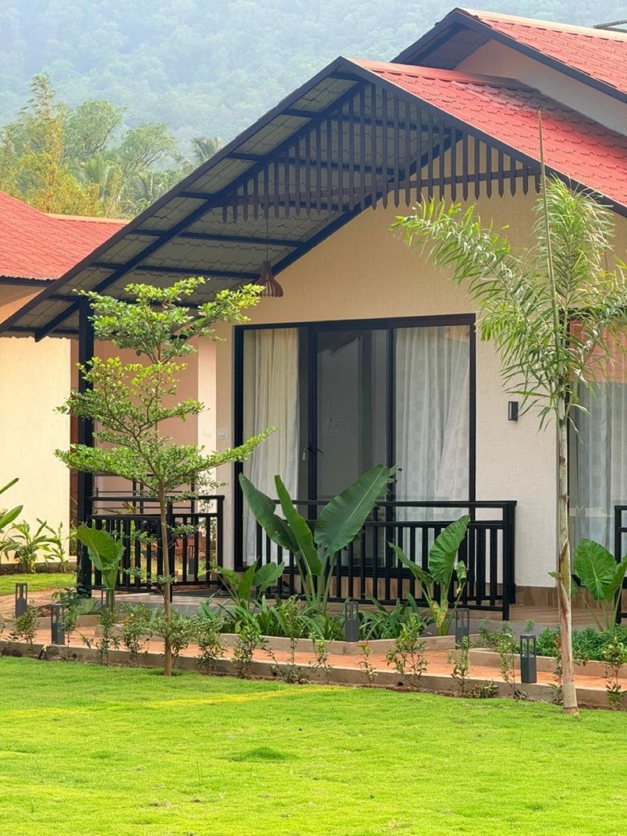 Nadi Teera cottage with red roof and lawn framed by hills