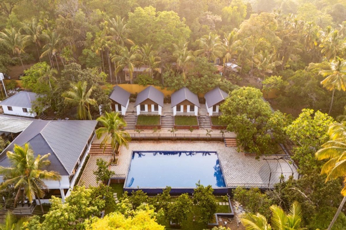 Aerial view of Vanatara Inn cottages and swimming pool amid palm greenery
